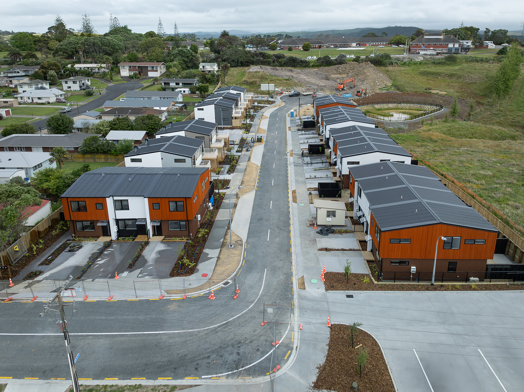 An aerial view of the completed terrace development, orange and white cladding along a new street