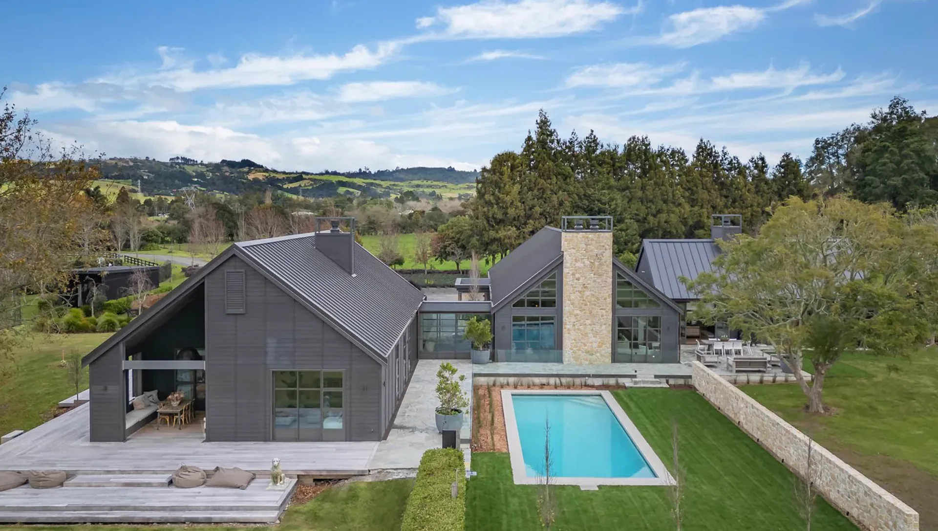An aerial view of the completed Clevedon home, its gable roofline, pool and grounds